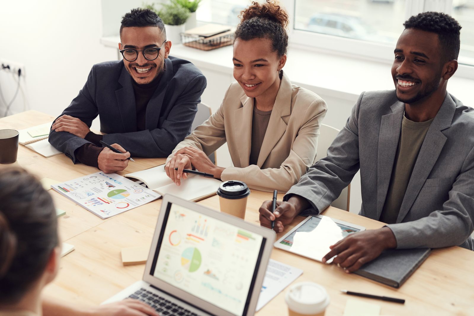 Consultants collaborating around a table with charts, notes, and coffee