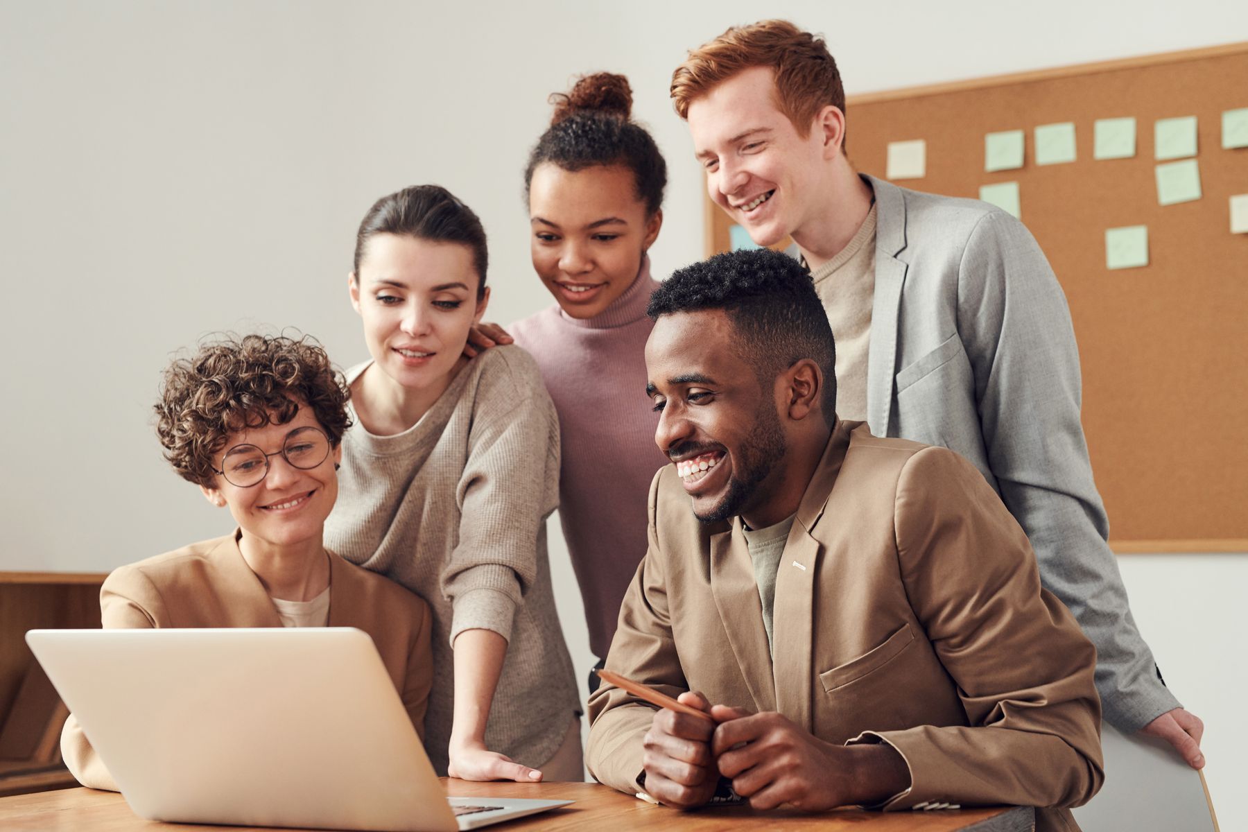 A consulting team gathered around a laptop during a working session